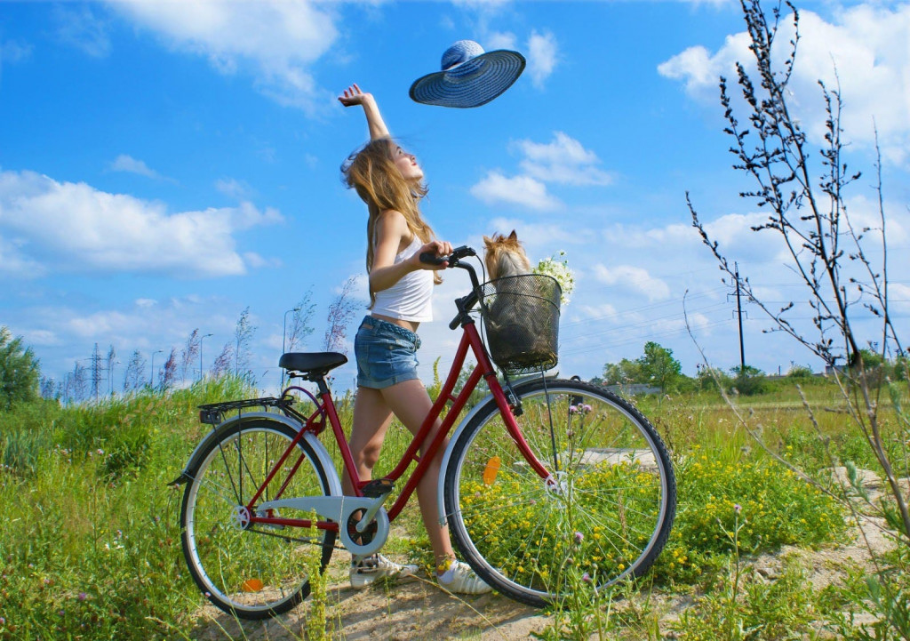 linda chica disfruta un día soleado a orillas de la ciudad con mascota en la bicicleta large
