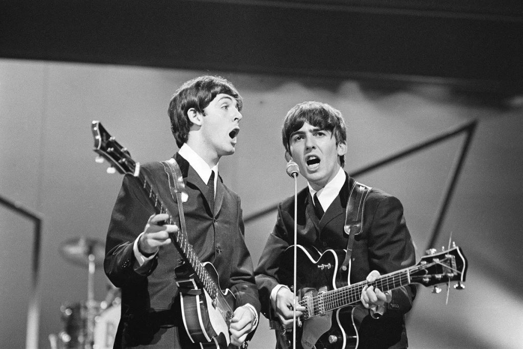 Paul McCartney y George Harrison en una presentacion en el London Palladium