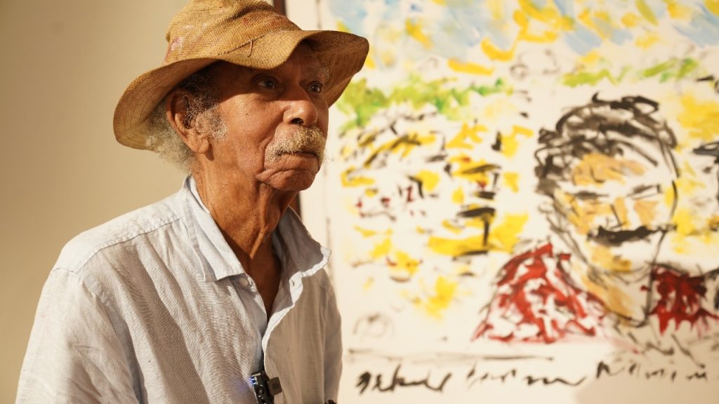 Jose Cestero junto a una de las pinturas de la exposicion Macondo en Santo Domingo