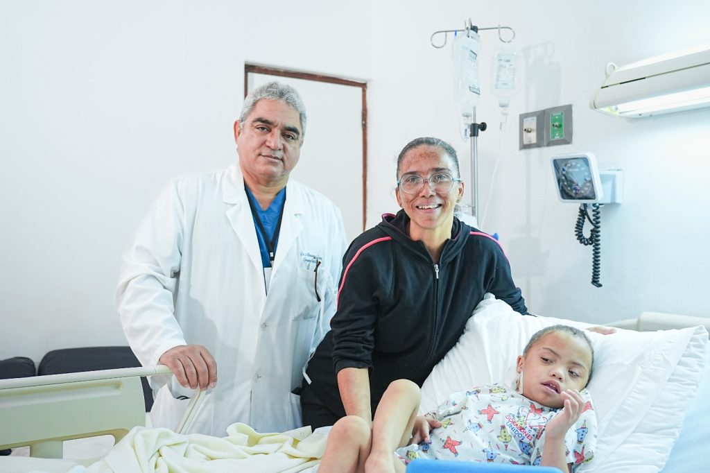 Cirujano cardiovascular Ramon Almanzar acompanando a nino reciente intervenido quirurgicamente juntoa su m